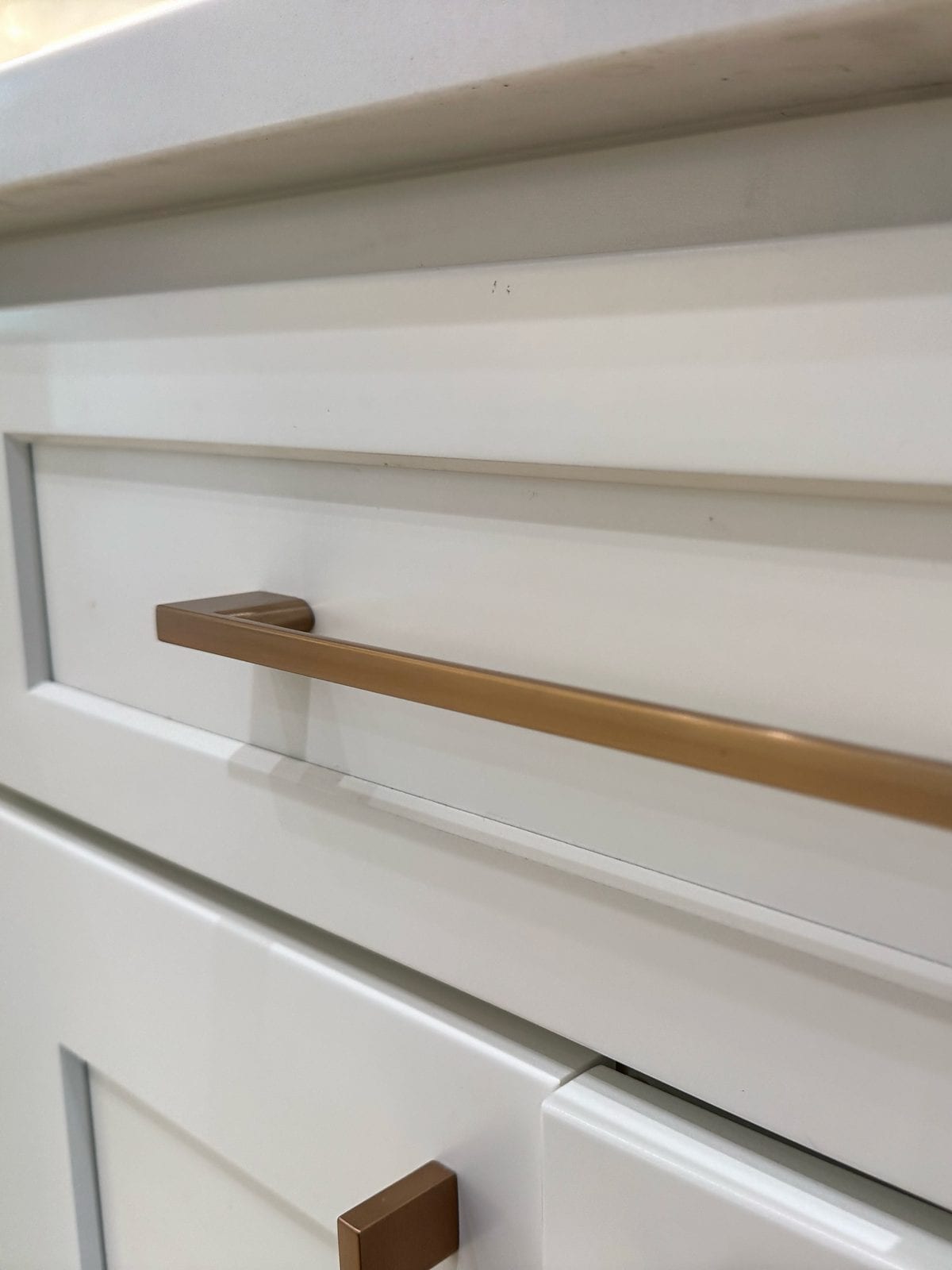 Close view of a warm metal pull on a painted shaker drawer front