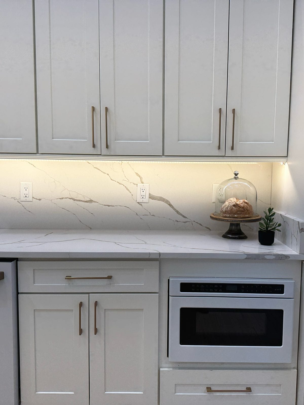 Finished cabinet run with a veined work surface and integrated appliance